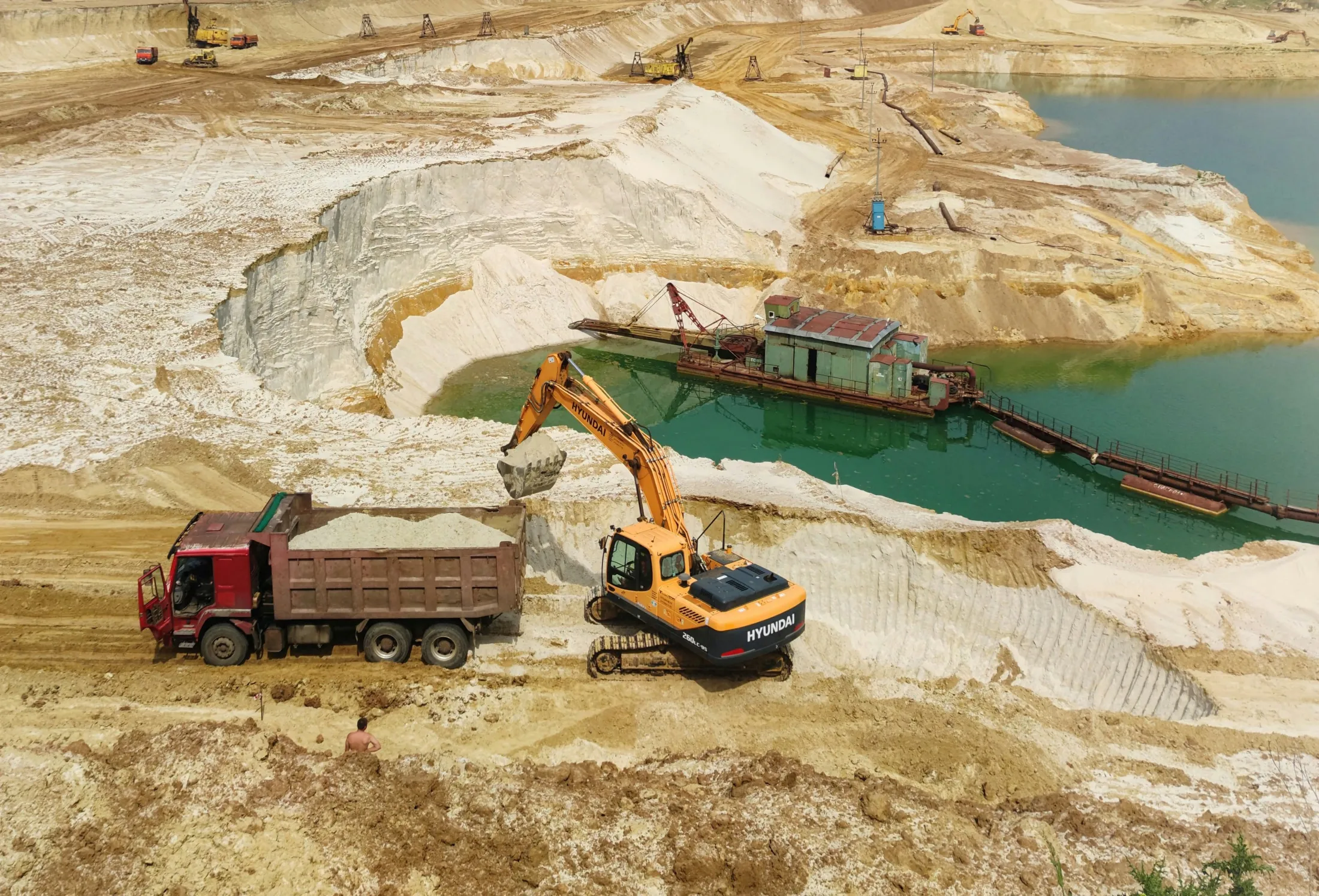 Large open-pit mine with excavators working across terraced benches